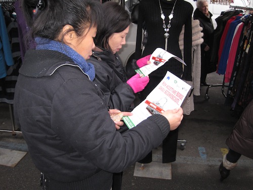 due ragazze cinesi leggono il contenuto del volantino contro l'abusivismo